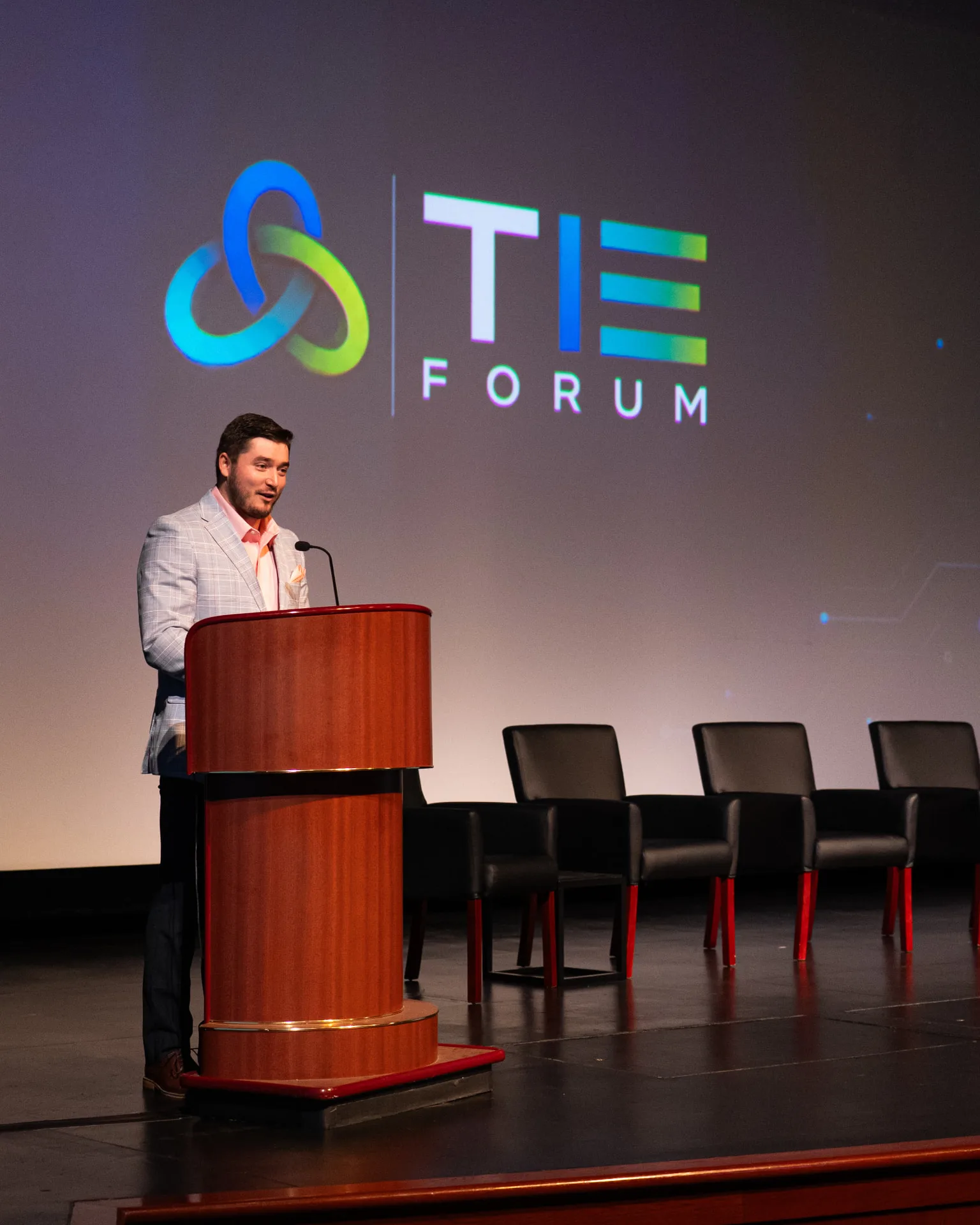 Tyler Dozier delivering remarks from a podium on stage during an event
