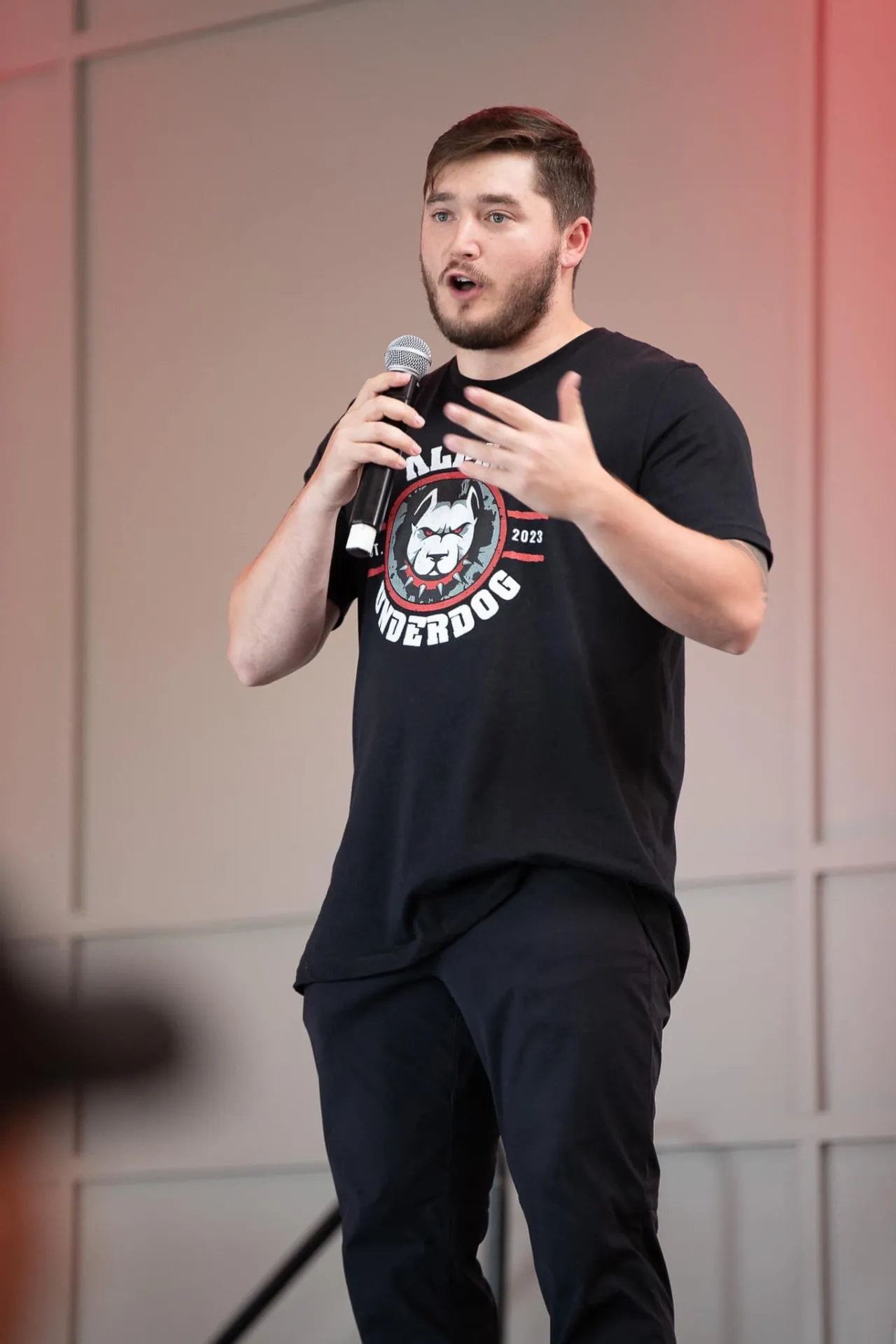 Tyler Dozier speaking to an audience with a handheld microphone